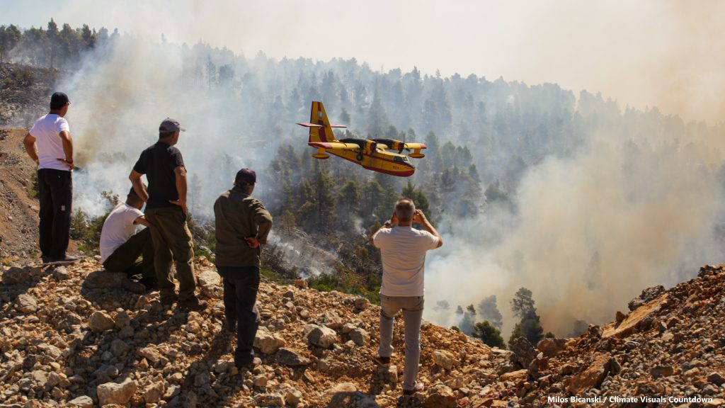 Locals look at burning forest during a wildfire on the island of Evia, Greece. When trees die by fire, they release into the atmosphere the carbon stored within them. This is why the effect of wildfires on emissions is among the most feared climate feedback loops â that the worldâs forests, which have typically been carbon sinks, would become carbon sources, unleashing all that stored gas.